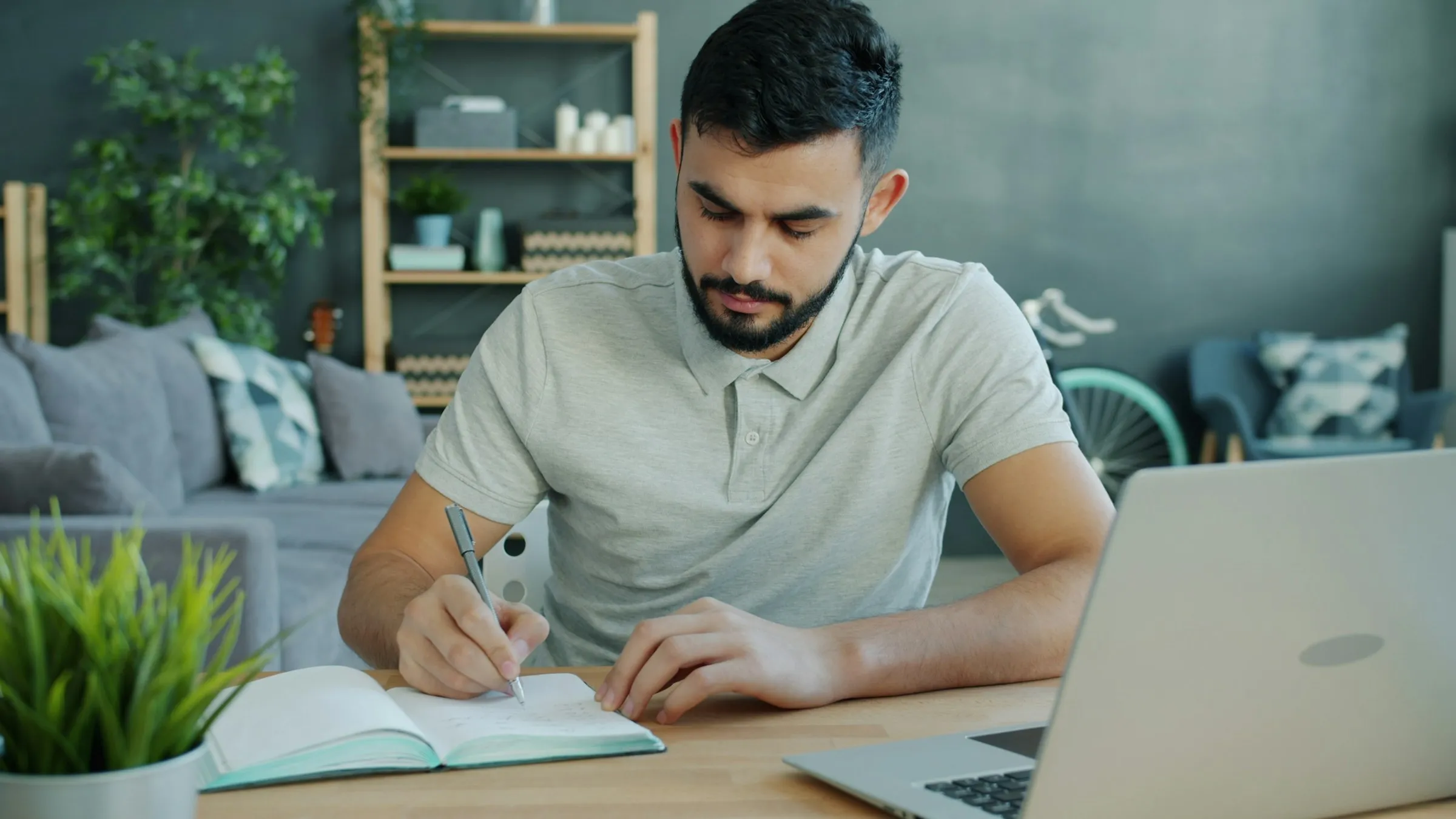 A man writing notes next to his laptop